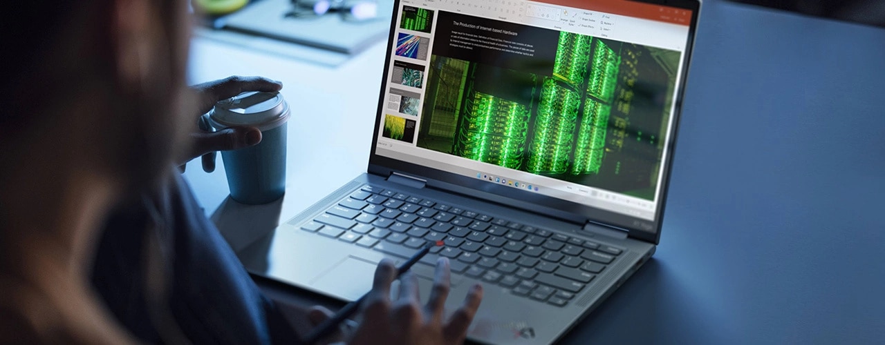 Portable Lenovo ThinkPad X1 Yoga Gen 8 2-en-1 utilisé en mode portable sur un bureau, avec des applications ouvertes à l’écran et le stylet intégré dans la main d’un homme.