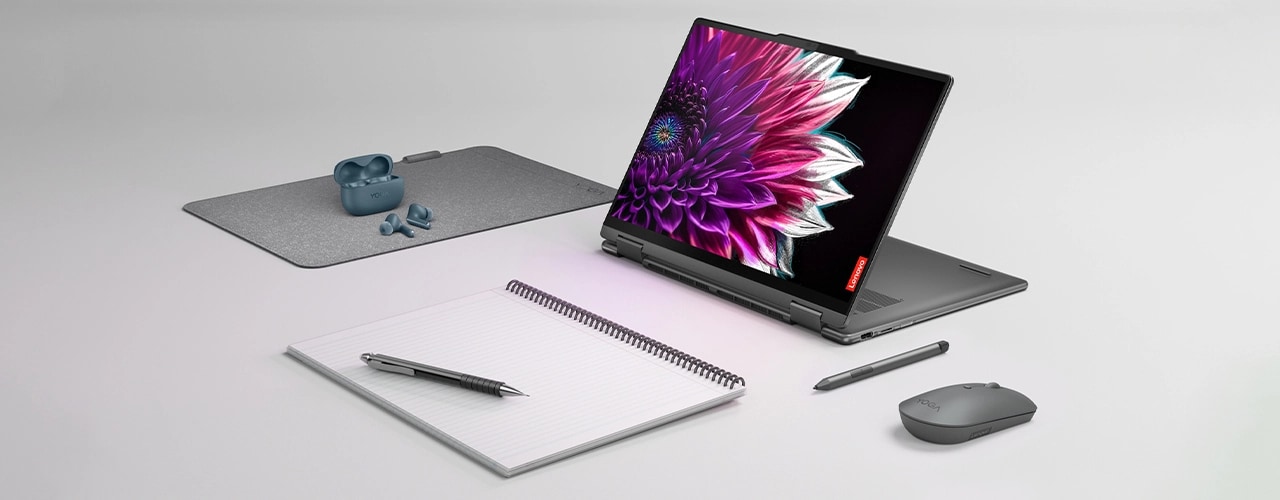 The Yoga 7 2-in-1 Gen 9 (14 Intel) in presentation mode, surrounded by a digital pen, a mouse, earbuds, and a notebook and pen