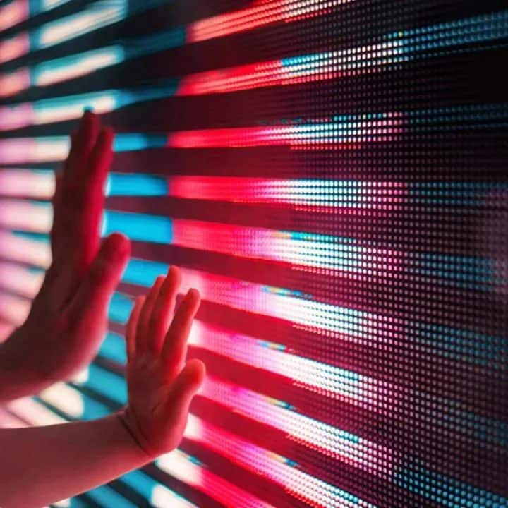 The hands of an adult and child touching an illuminated screen