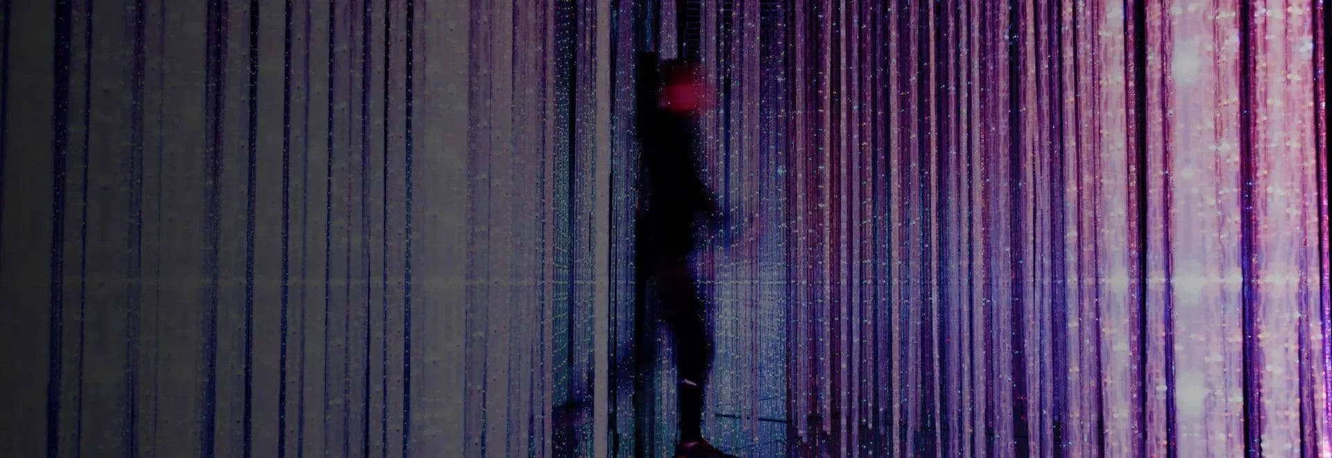 A blurry abstract of a person walking amongst a colorful backdrop