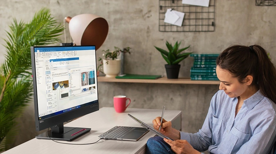 A person multitasking with Lenovo ThinkBook Plus Gen 5 Hybrid (14” Intel) Tablet using the magnetic stylus while connecting the base to an external monitor for carrying out multiple tasks.