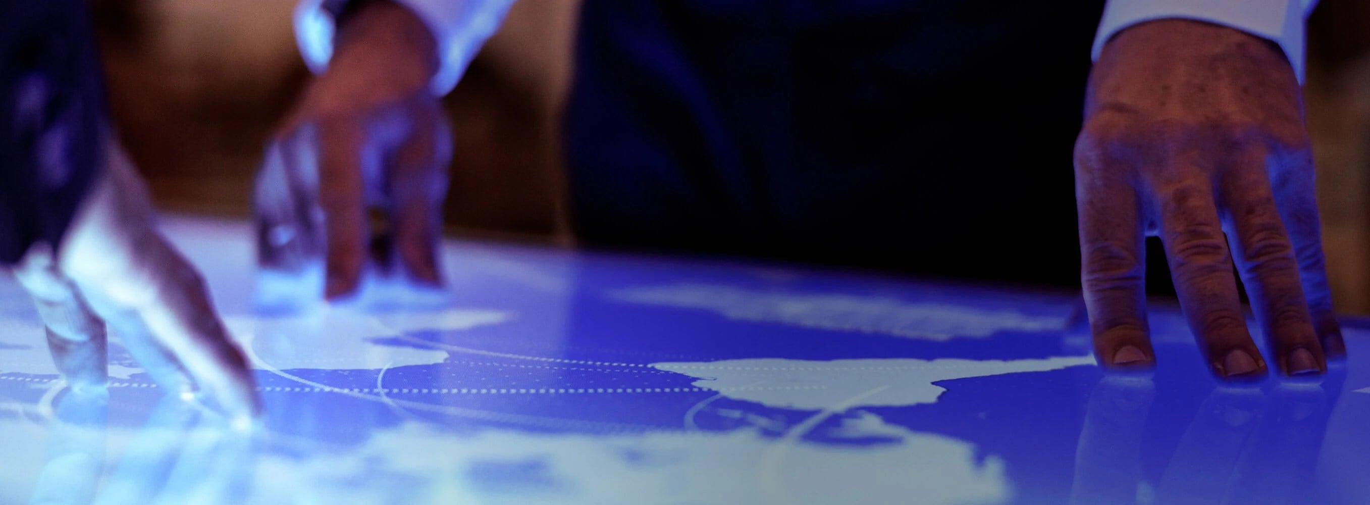 Hands interacting with a touch-screen map of the globe