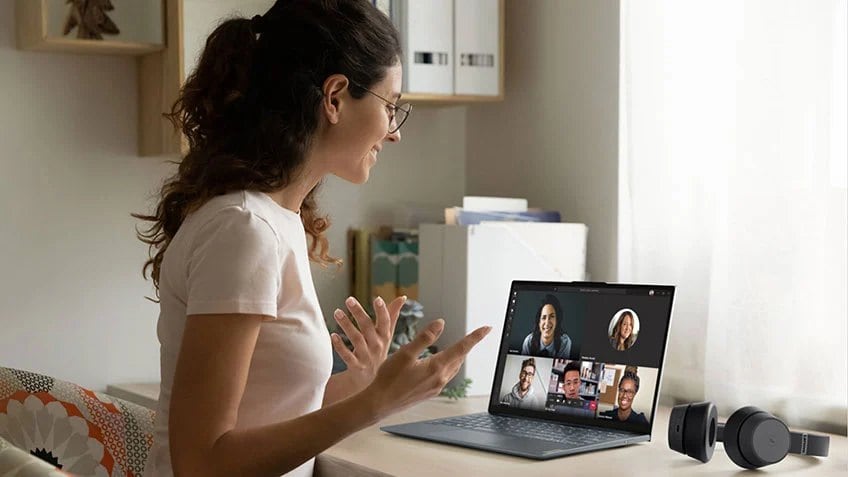 A student in her dorm room having a video chat on her laptop with friends