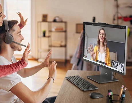 A group of people smiling and looking at a woman on a video call on a Lenovo IdeaCentre AIO Gen 10 (24" AMD) all-in-one Copilot+ PC in Luna Grey on a desk