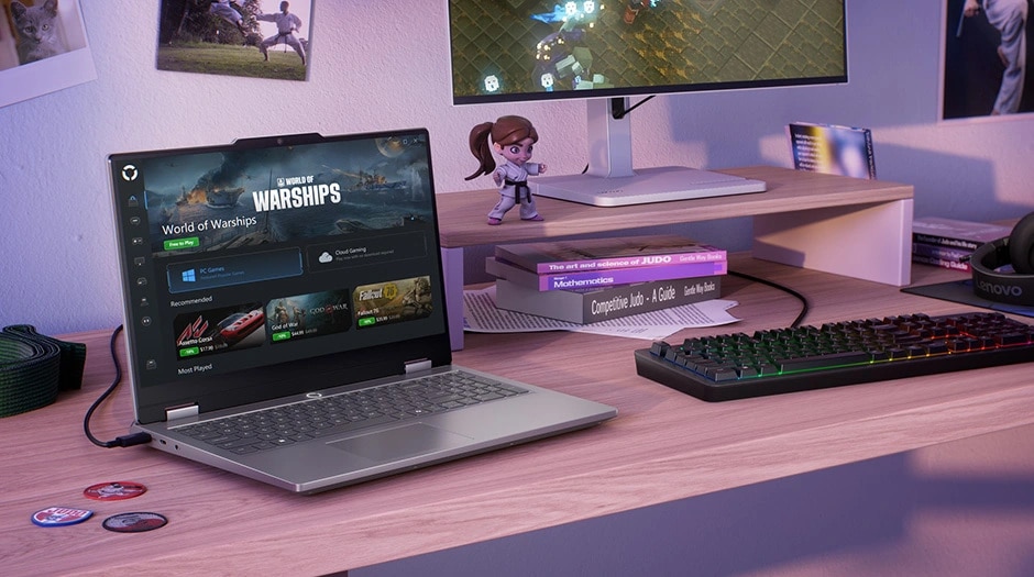Lenovo LOQ Essential 15IRX11 gaming laptop on a desk with mouse, keyboard, mousepad, and monitor – left-front view, lid open, with Legion Space Game Store screen on the display.