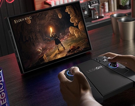 Controllers docked to a grip while the display shows 'Elden Ring' on the handheld, Lenovo Legion Go Gen 2. 