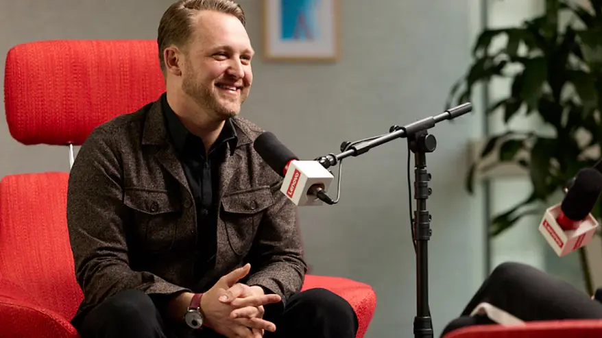 Robert Daigle in a red chair talking into a microphone.