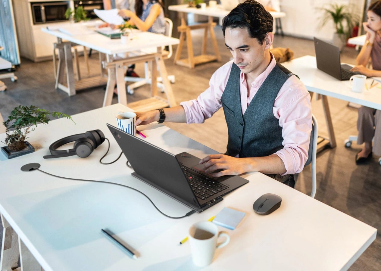 Homme utilisant des accessoires Lenovo Go dans un environnement de bureau partagé