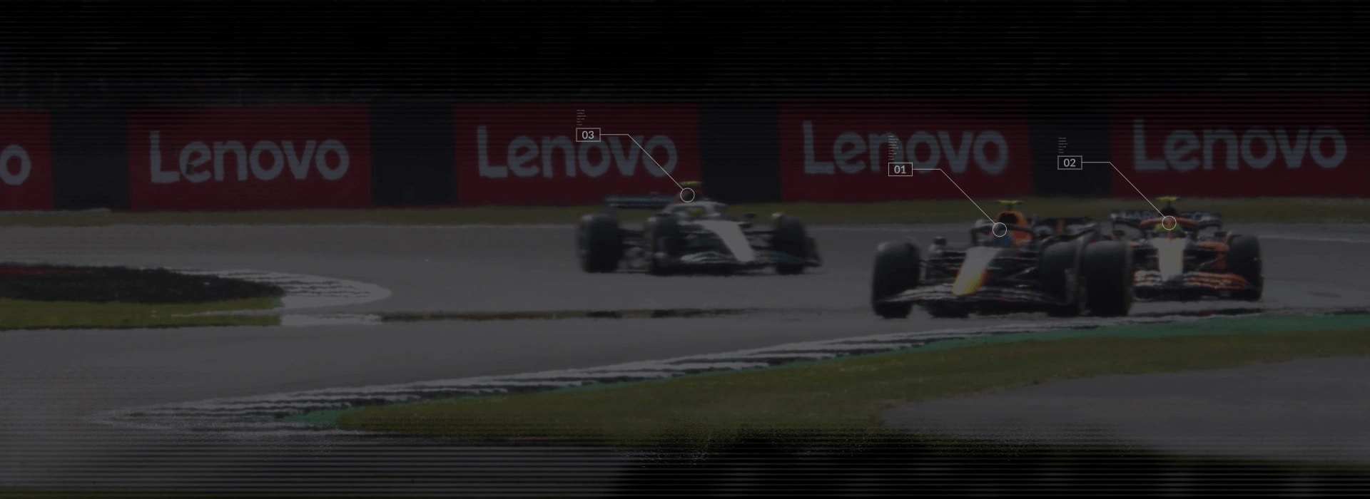 3 машини F1 на гоночному треку з банерами Lenovo на задньому плані