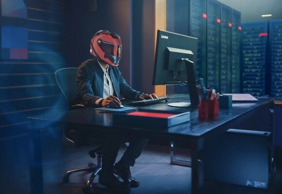 Человек в гоночном шлеме решает задачи на рабочей станции ThinkStation в центре обработки данных.