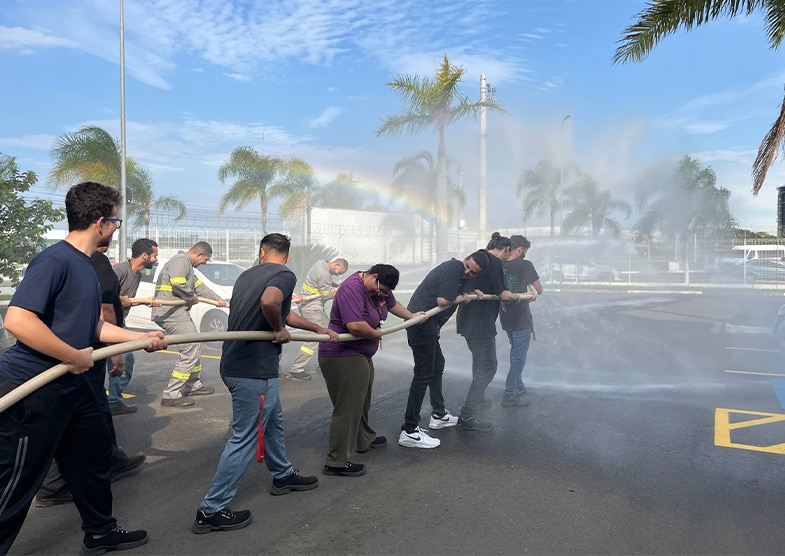 Two fire or safety crews using large hoses to spray down a parking lot.
