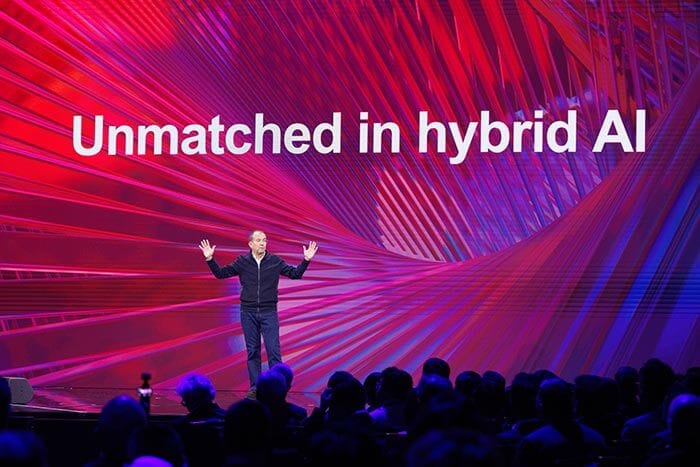 Luca Rossi on stage in front of a screen that reads “Unmatched in hybrid AI' with a visually dynamic background.