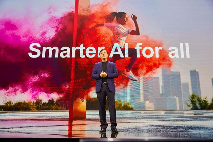 Lenovo CEO Yuanqing Yang stands in front of a backdrop that reads 'Smarter AI for all' with vibrant colors.