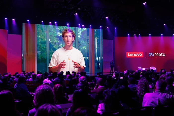 O CEO da Meta, Mark Zuckerberg, fazendo uma apresentação remotamente em uma grande tela com as marcas Lenovo e Meta.