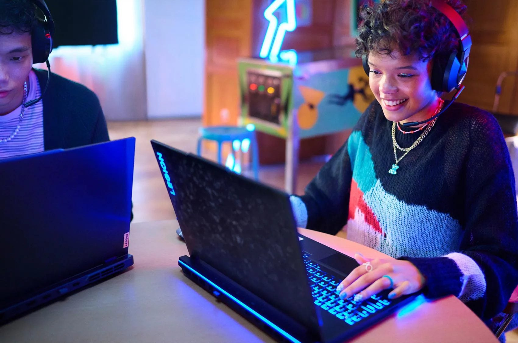 A young woman wearing Legion headphone playing on a Legion laptop.