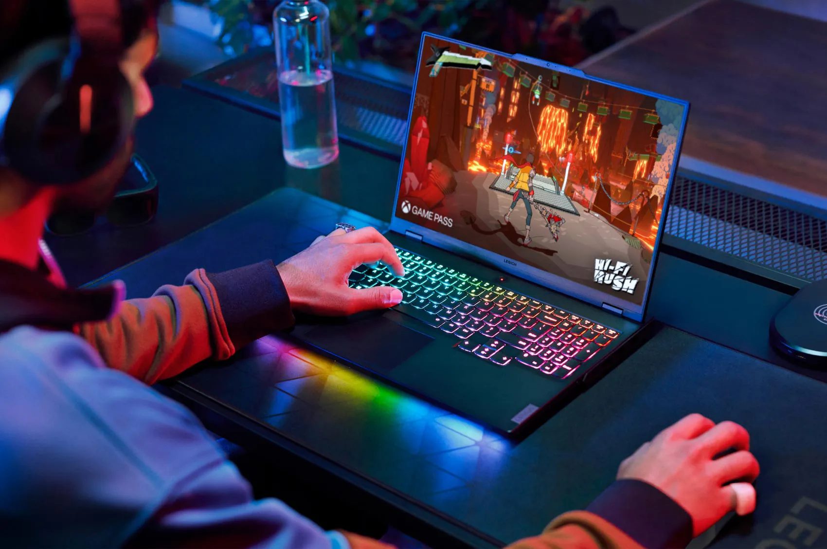 An over-the-shoulder view of a man playing first person action game on a Legion laptop.