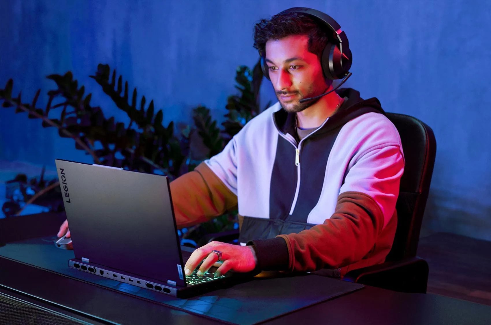 A man wearing a Legion headset with microphone playing on his Legion laptop.