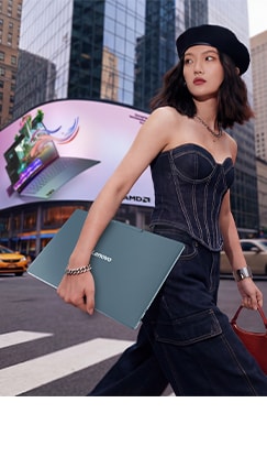 A stylish woman holding a Lenovo Yoga laptop walks along a city street, with a large Lenovo Yoga outdoor digital display in the background.
