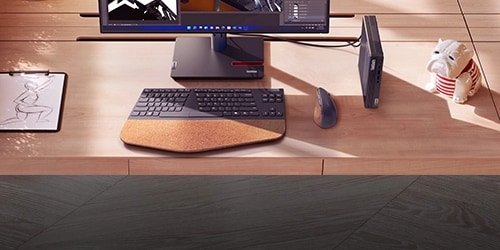 A Lenovo Tiny Desktop placed on a desktop next to a monitor, mouse, and keyboard. 