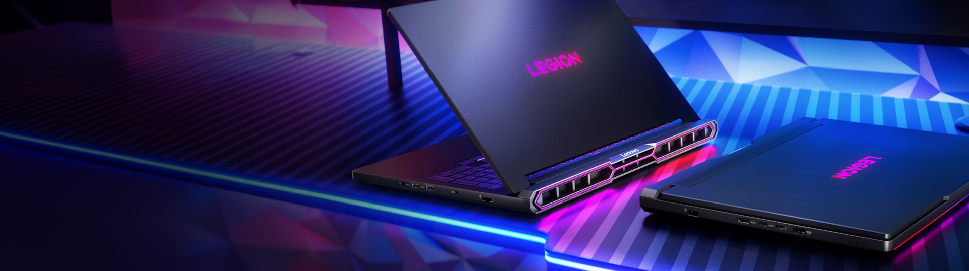 Two Legion Laptops on a desk, one on the left open and the one on the right closed with RGB keyboard glow
