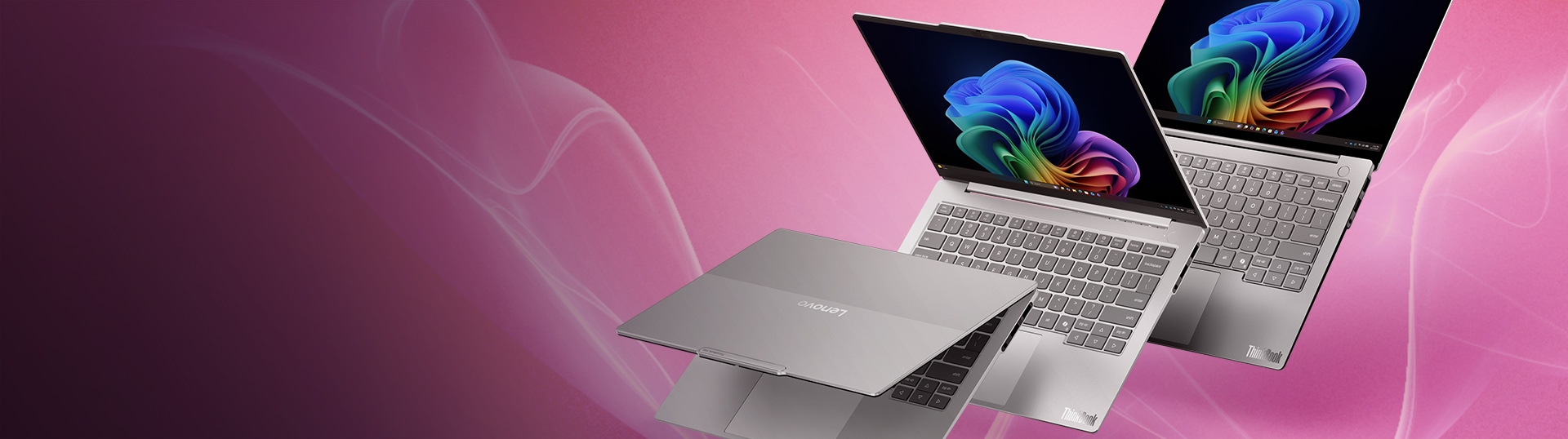 Three silver Lenovo ThinkBook laptops displayed at different angles against a pink gradient background, showcasing the slim design, keyboard, and vibrant colorful displays.