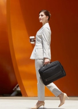 A confident businesswoman walking with her Lenovo ThinkPad X1 Carbon laptop and carrying case.