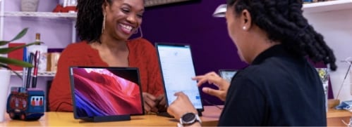 Two women laughing and using Lenovo Tablet for work