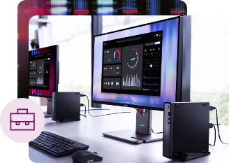 Two desktop workstations with Lenovo monitors displaying data dashboards, paired with compact Lenovo ThinkCentre PCs and keyboards, set up on a white desk in a bright modern office