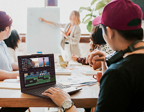 A student in a classroom, working on the Lenovo ThinkPad P14s Gen 7 (14" AMD) mobile workstation laptop editing a video project.