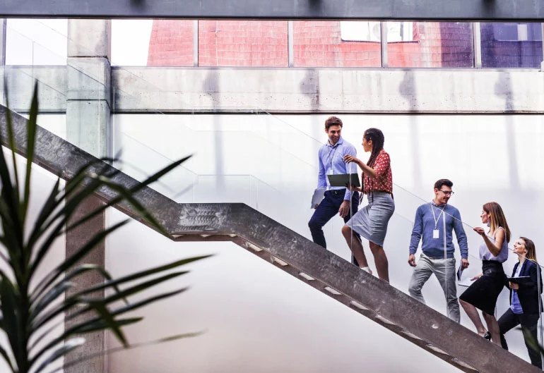 Five people, three women and two men, walking up stairs that start at the bottom right side of the image and end at the top left of the image.