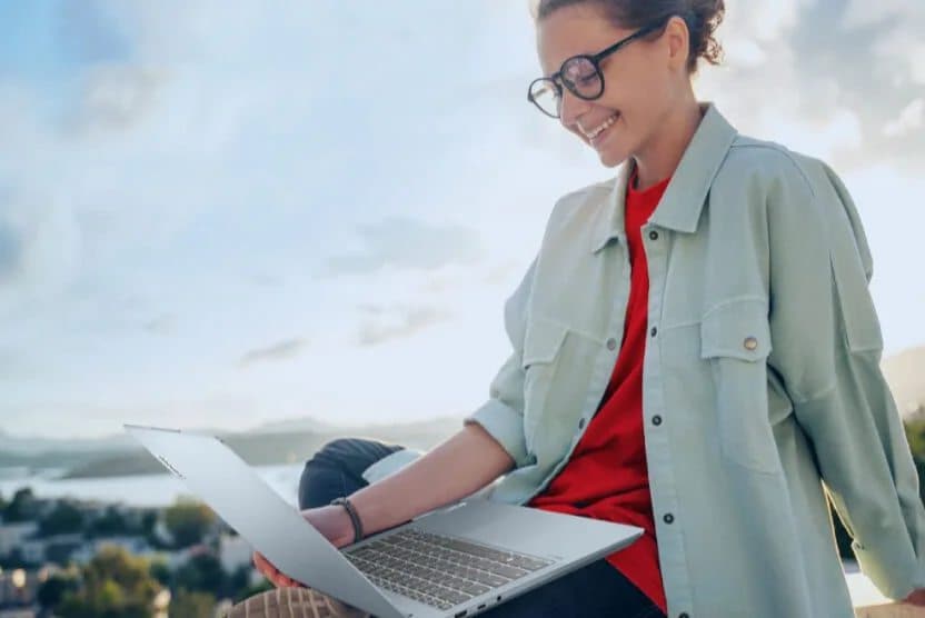 A woman using a Lenovo laptop outdoors.