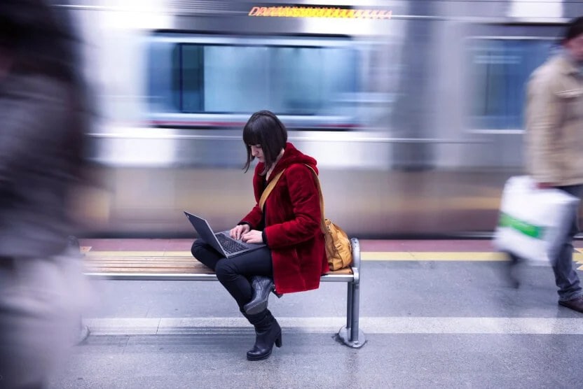 A woman using a Lenovo laptop in a subway station.