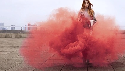 Person standing semi engulfed by reddish smoke.
