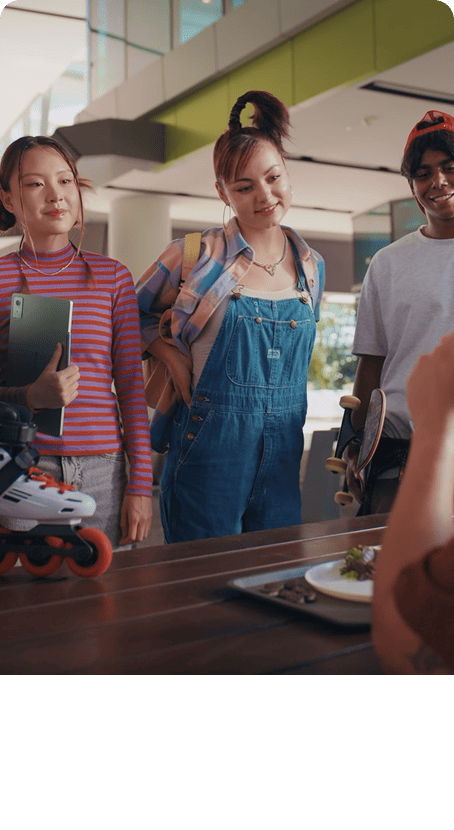 A group of young students wealk through a campus hallway, with one woman holding her tablet.