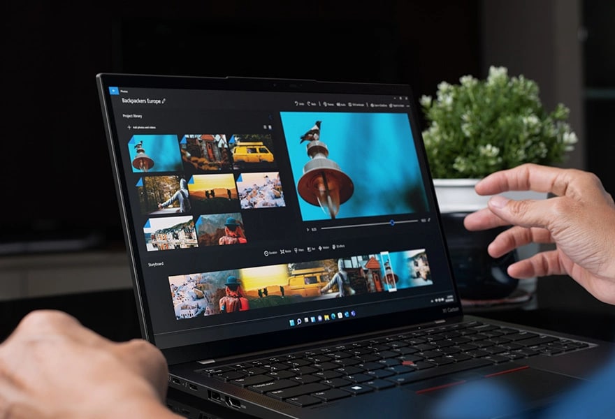 Close up of hands interacting with the Lenovo ThinkPad X1 Carbon Gen 11 laptop open, showing images & video on the display.