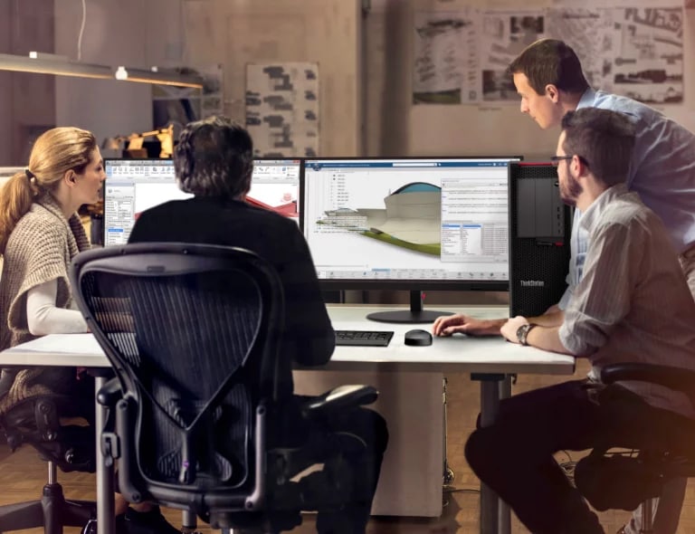 Two white men hovering over a desk where someone uses the Lenovo ThinkStation P620 tower workstation with dual monitors showing CAD rendering.