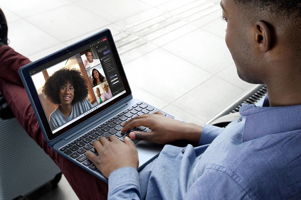 Någon som deltar i ett konferenssamtal med en bärbar Windows 10-företagsdator från Lenovo i knät