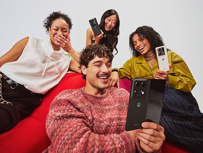Three motorola razr fold phones, one with its display opened up, stand atop a reflective surface.