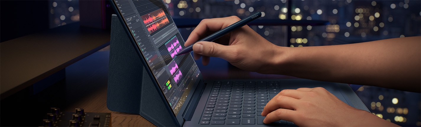 A pair of hands draws on the display of a Lenovo Yoga laptop. 