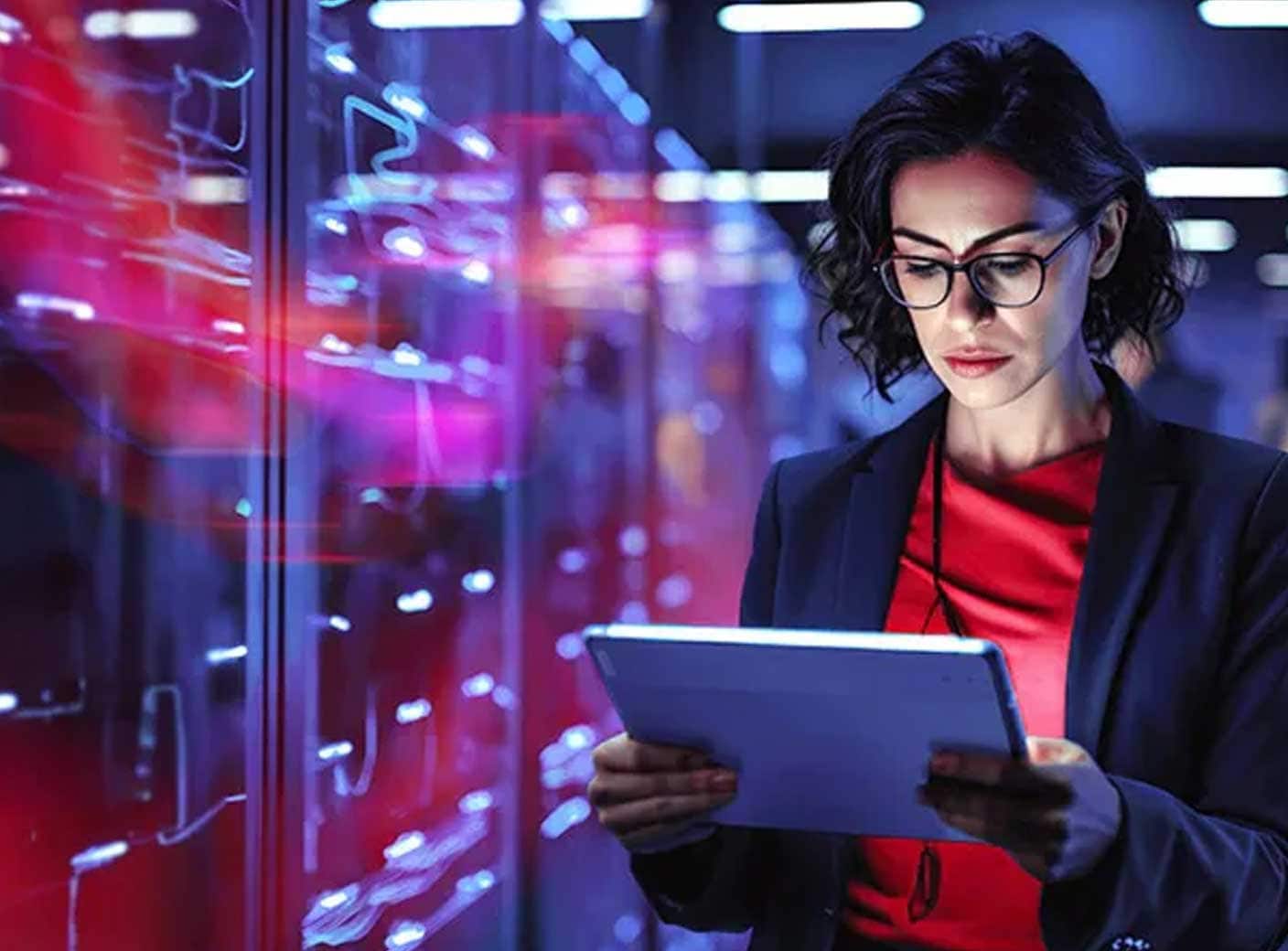 暗いサーバールームで、タブレットを見ている女性。