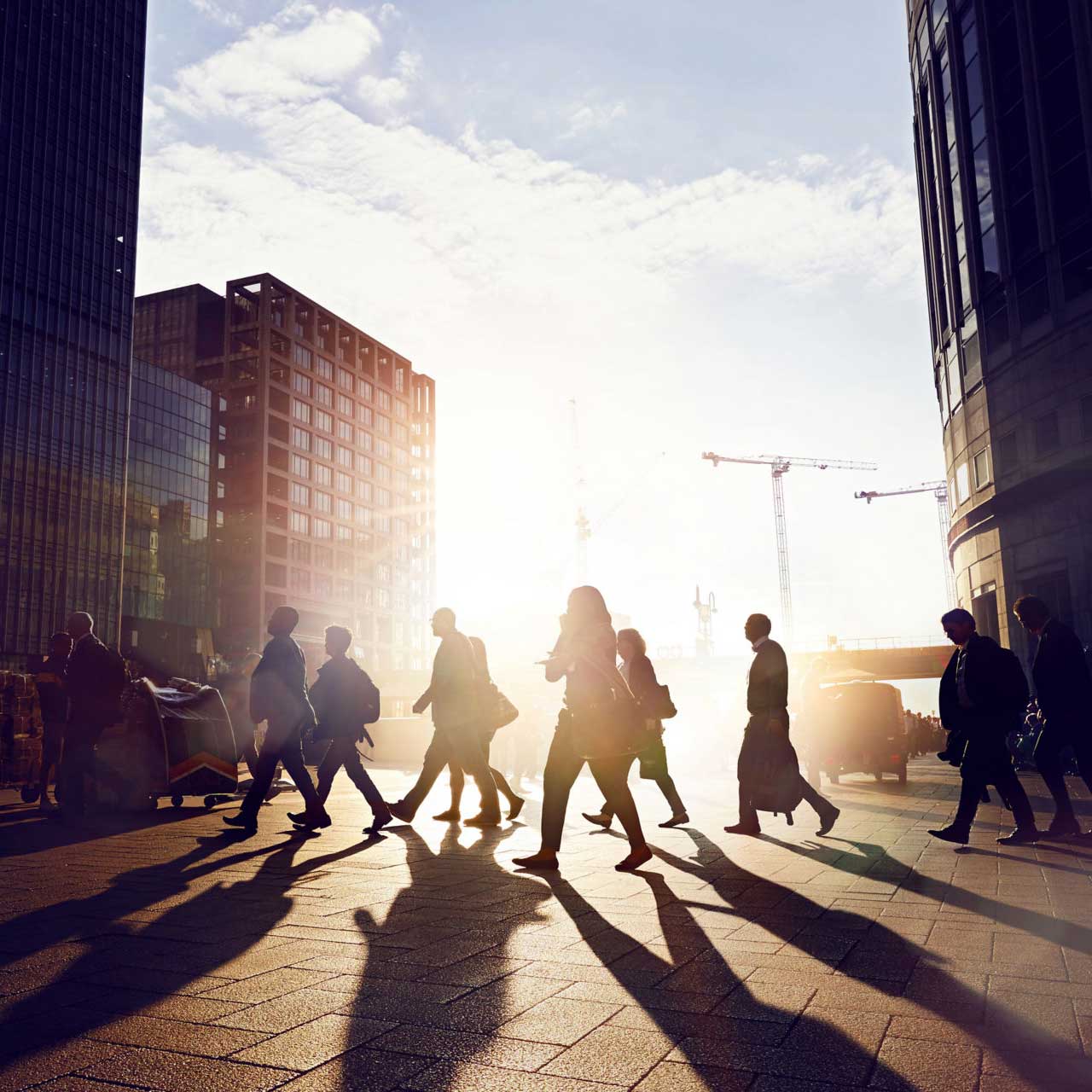 Des gens silhouettes qui traversent une rue de la ville en matinée.