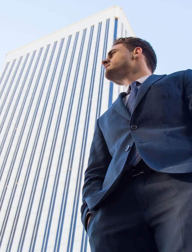 Image of a businessman standing in front of a tall building.