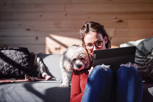 Woman sitting on the floor with her dog working on a laptop