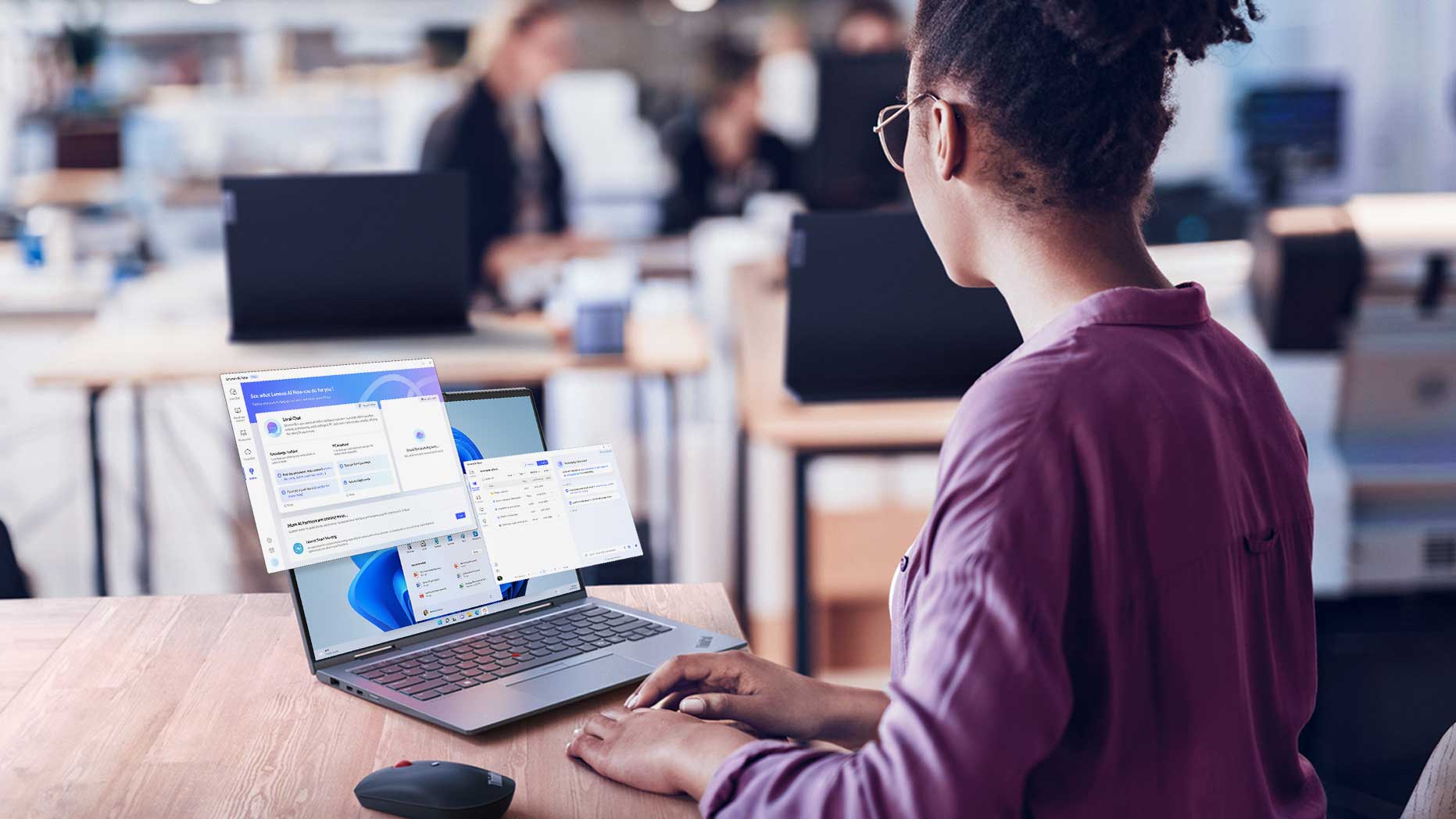 A woman in an office typing on a laptop with screens popping out.