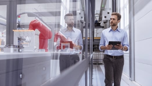 A man with a tablet examines robotics from a hallway