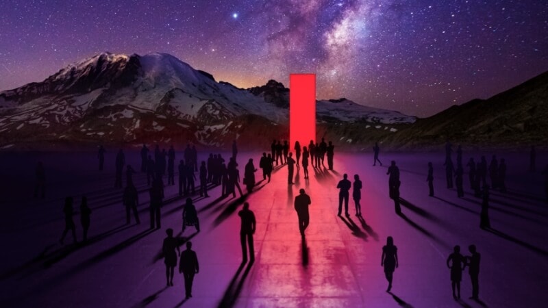 Silhouetted figures walking toward a striking glowing red light, set against a majestic mountain backdrop.