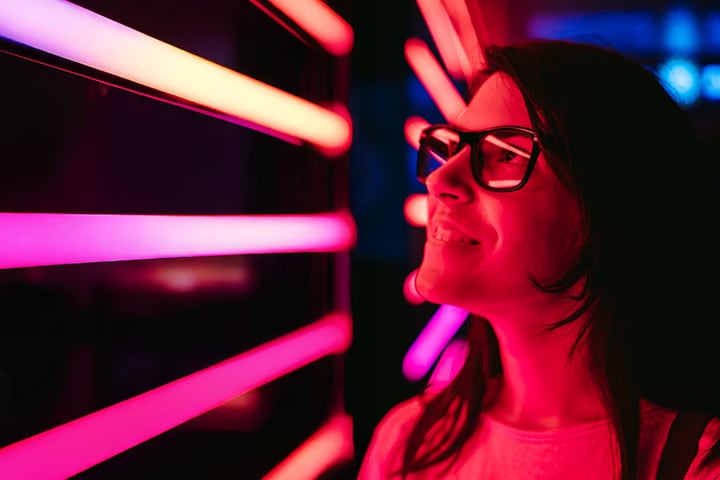 Image of a person near vibrant pink and orange neon lights.