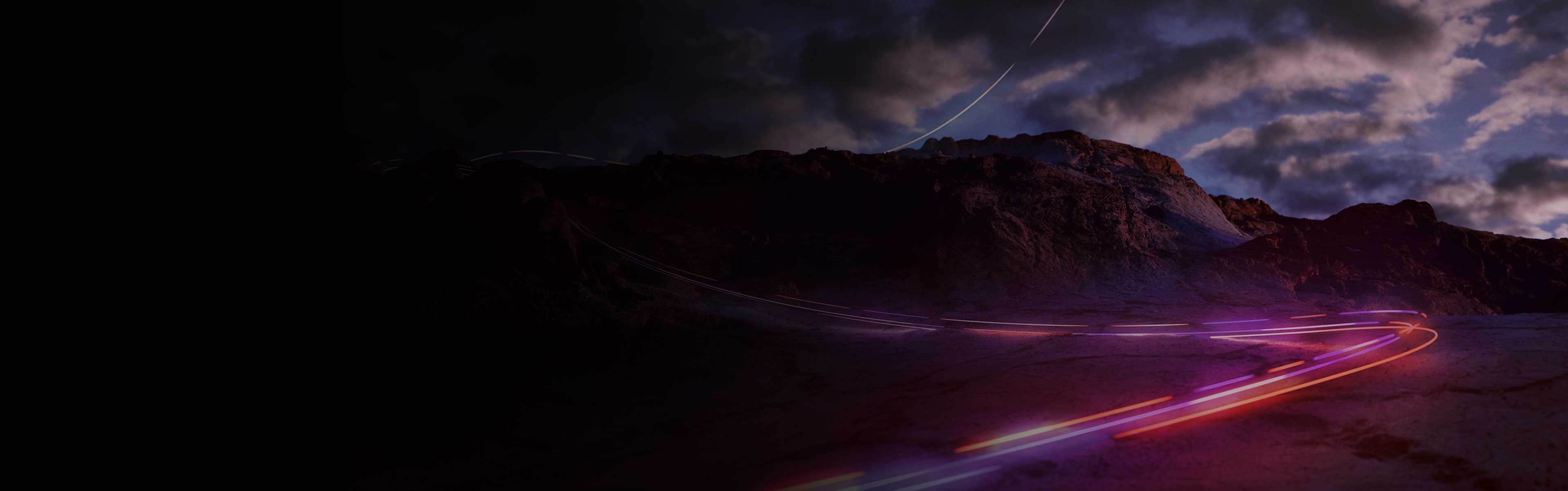 Purple and red lights along a road leading into a mountain. 