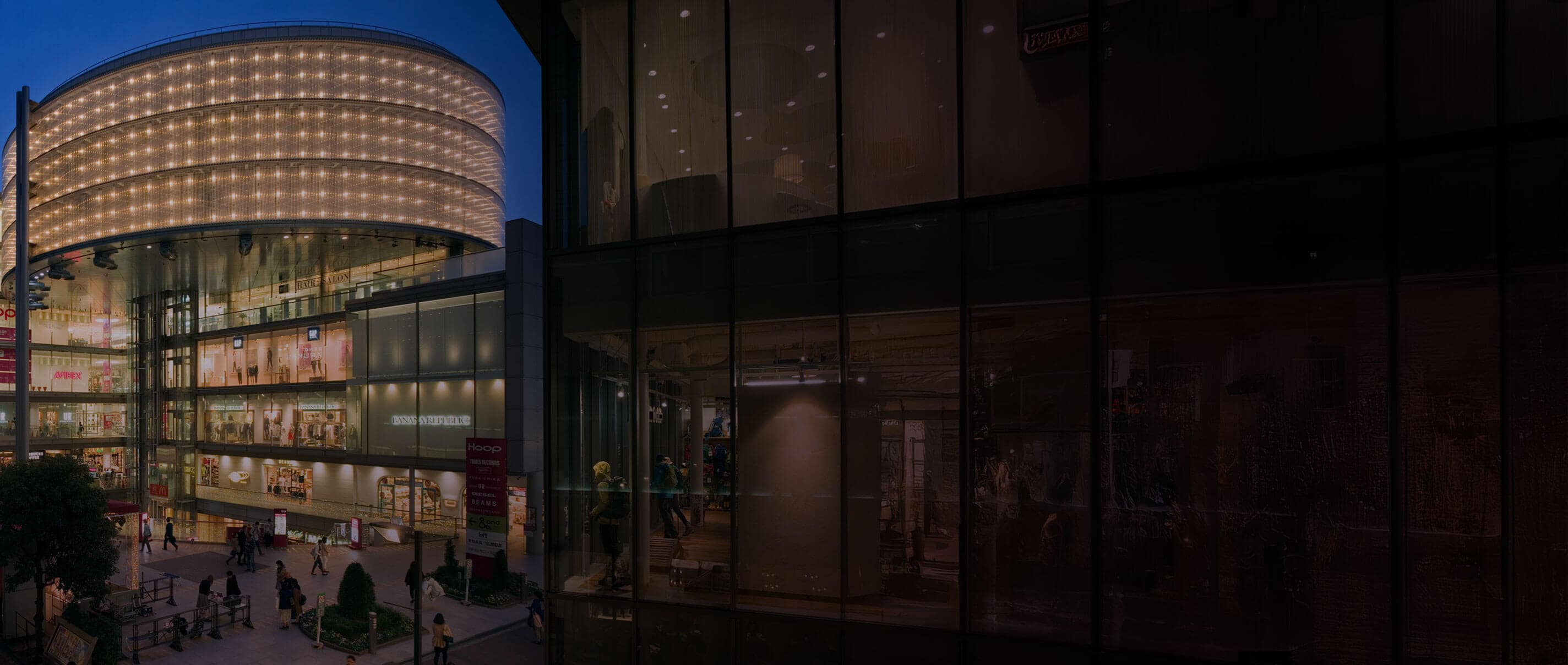 Un edificio comercial moderno curvo y de varios pisos al anochecer.
