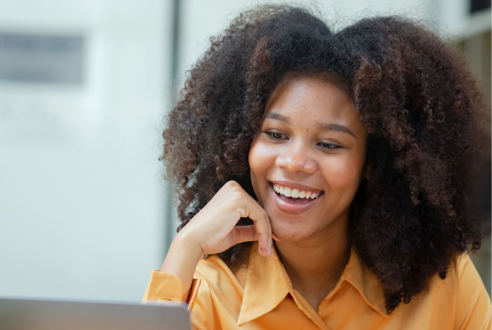 A woman smiling and resting her chin on her hand